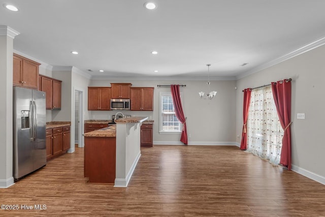 kitchen with appliances with stainless steel finishes, dark wood-type flooring, ornamental molding, and an inviting chandelier