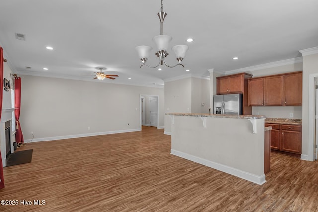 kitchen featuring brown cabinets, a fireplace, stainless steel refrigerator with ice dispenser, visible vents, and a kitchen bar