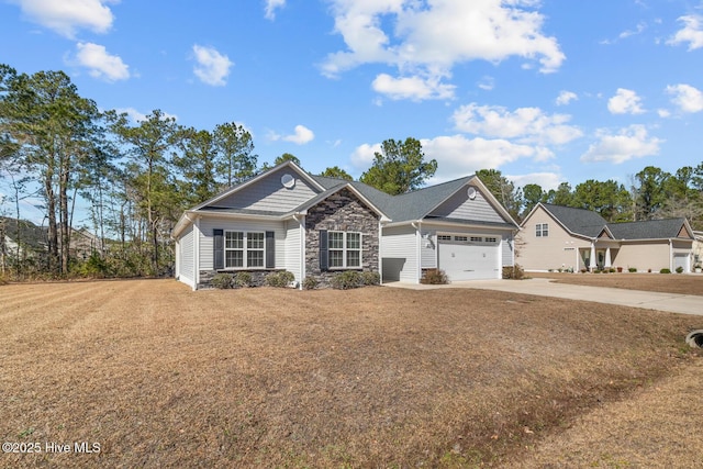 view of front of home featuring a front yard, stone siding, driveway, and an attached garage