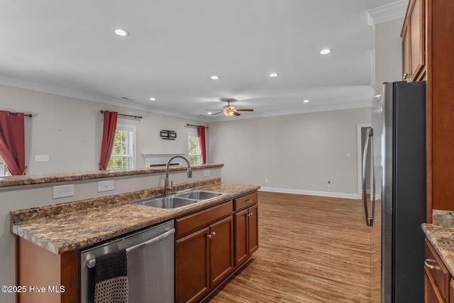 kitchen with stainless steel appliances, brown cabinetry, crown molding, and a sink