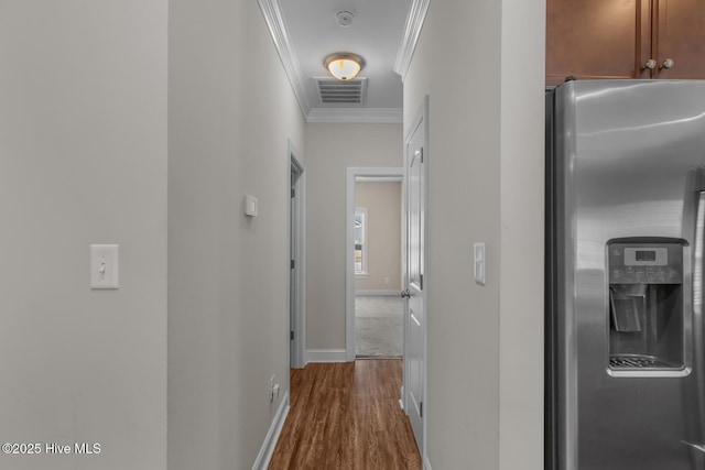 hallway featuring dark wood finished floors, visible vents, crown molding, and baseboards