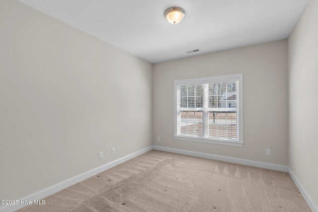 unfurnished room with baseboards, visible vents, and light colored carpet