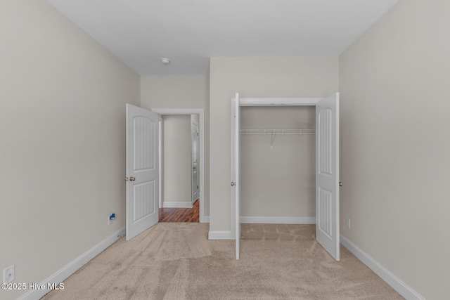 unfurnished bedroom with carpet floors, a closet, and baseboards