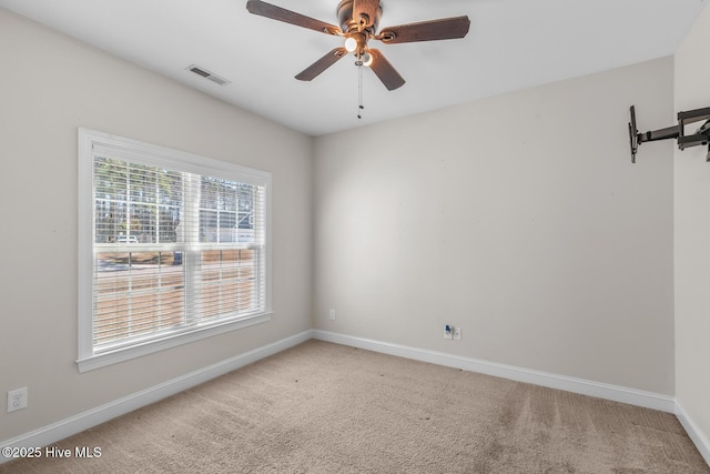 spare room with baseboards, ceiling fan, visible vents, and light colored carpet