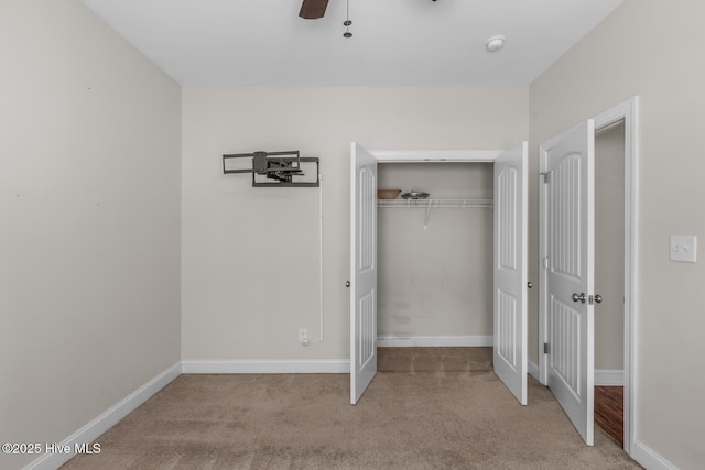 unfurnished bedroom with a closet, carpet flooring, ceiling fan, and baseboards