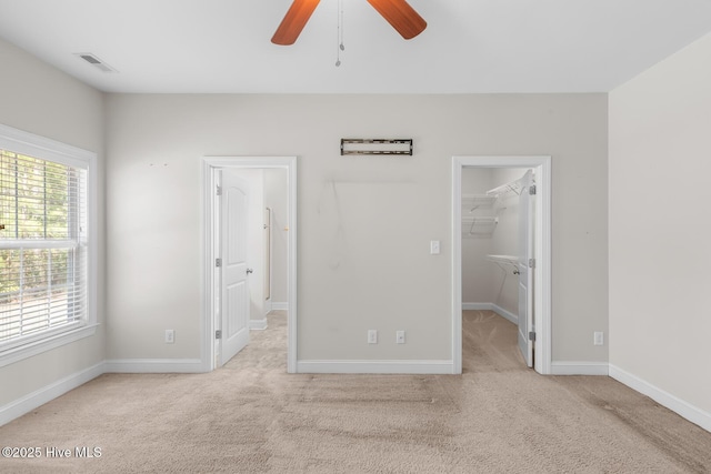 unfurnished bedroom featuring visible vents, baseboards, ceiling fan, carpet, and a spacious closet