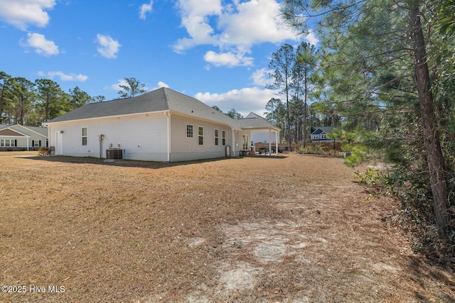 back of house featuring central AC unit and a lawn