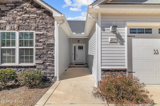 property entrance featuring a garage, stone siding, and roof with shingles