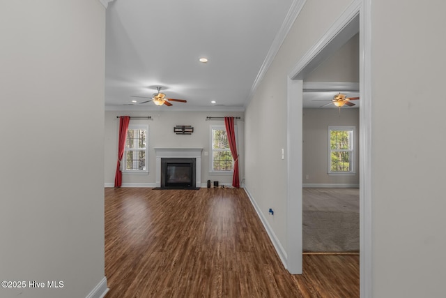 unfurnished living room with a healthy amount of sunlight, a fireplace with flush hearth, and crown molding