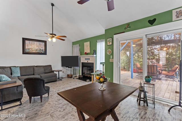 living area featuring a fireplace with flush hearth, vaulted ceiling, and a ceiling fan