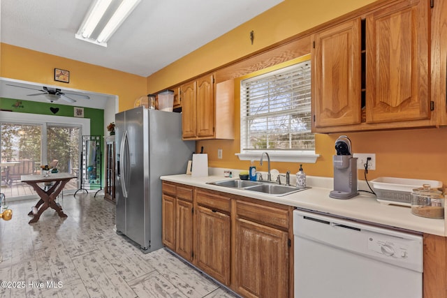 kitchen with light countertops, stainless steel fridge, dishwasher, and a sink