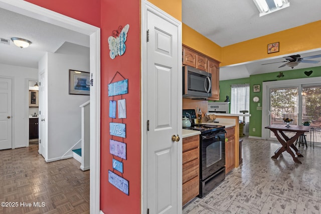 kitchen with light countertops, stainless steel microwave, visible vents, brown cabinetry, and black / electric stove