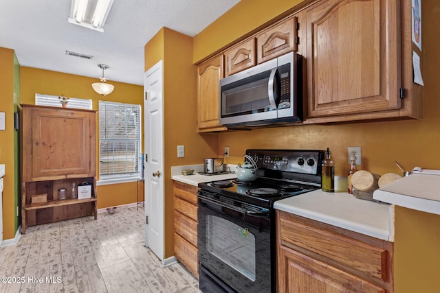 kitchen with light countertops, black / electric stove, stainless steel microwave, and visible vents