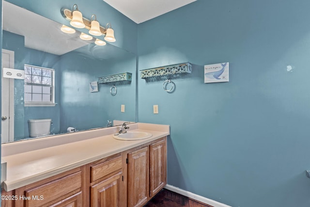 bathroom featuring baseboards, vanity, and toilet