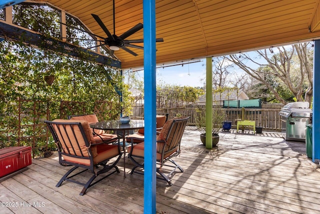 wooden deck featuring outdoor dining area, ceiling fan, grilling area, and fence