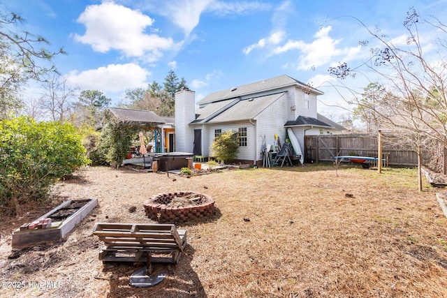 rear view of property with fence private yard, a hot tub, a trampoline, and a chimney