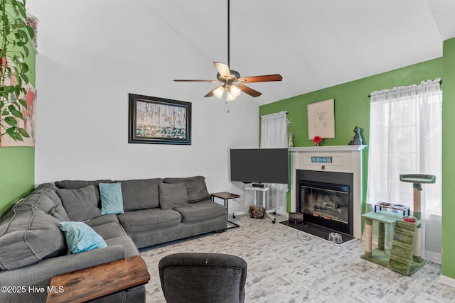 living room featuring a fireplace with flush hearth, vaulted ceiling, baseboards, and ceiling fan