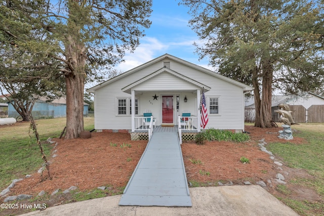 bungalow-style home featuring a front lawn, fence, and covered porch