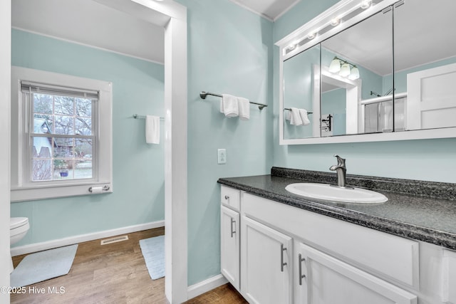 bathroom with vanity, wood finished floors, visible vents, baseboards, and toilet