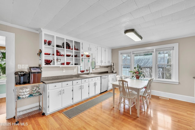 kitchen featuring white cabinetry, light wood finished floors, a sink, dishwasher, and dark countertops