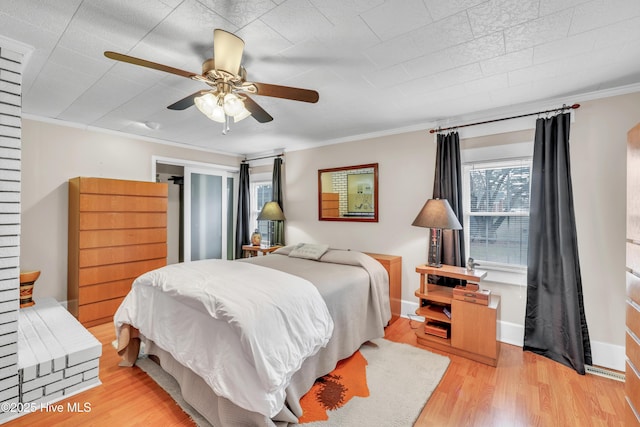 bedroom with light wood-style flooring, a ceiling fan, baseboards, and ornamental molding