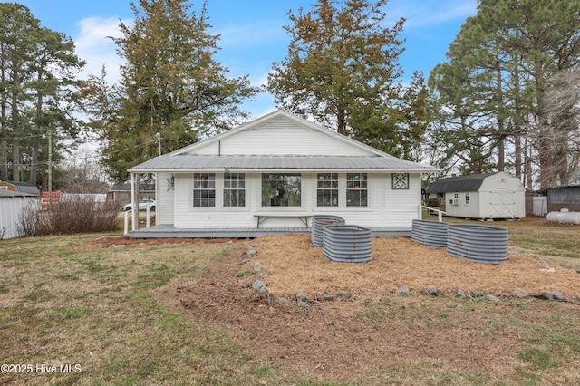 back of house featuring metal roof, an outbuilding, a storage shed, and fence