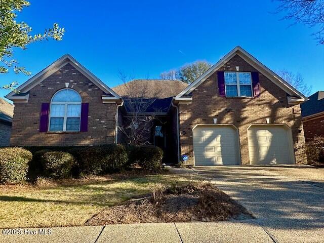 view of front of house featuring driveway, brick siding, and an attached garage