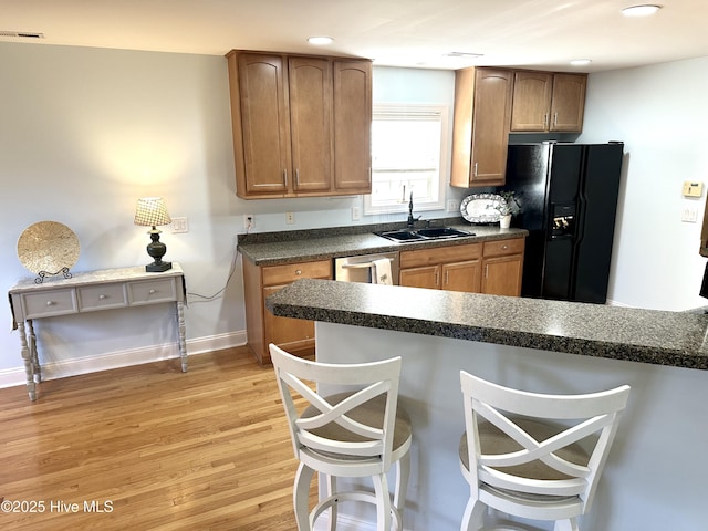 kitchen featuring dark countertops, visible vents, a sink, a kitchen bar, and black fridge