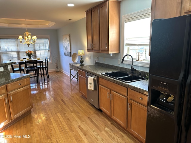 kitchen featuring a sink, light wood-type flooring, dishwasher, black refrigerator with ice dispenser, and a raised ceiling