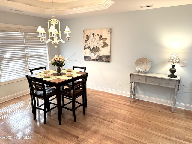 dining area featuring baseboards, light wood finished floors, visible vents, and a notable chandelier