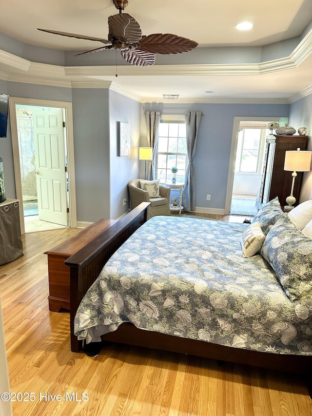 bedroom with baseboards, a tray ceiling, crown molding, and wood finished floors