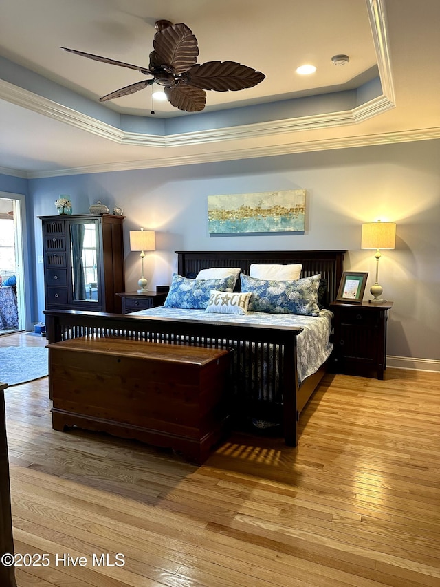 bedroom with ornamental molding, a raised ceiling, and hardwood / wood-style floors