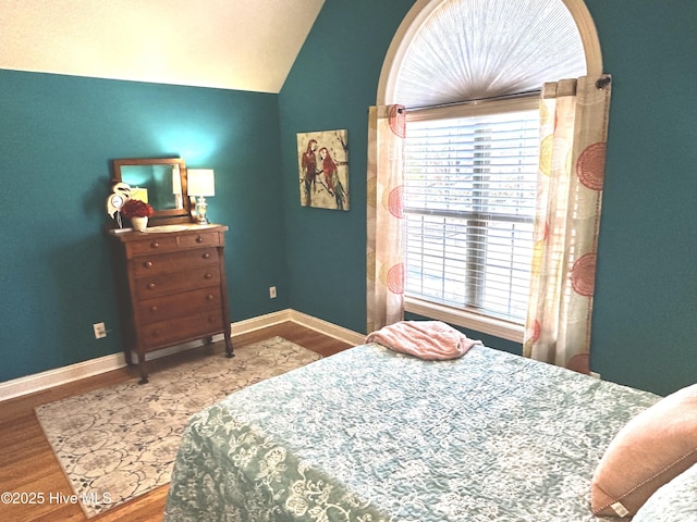 bedroom featuring lofted ceiling, baseboards, and wood finished floors