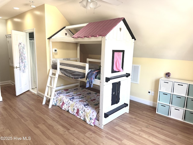 bedroom featuring visible vents, vaulted ceiling, baseboards, and wood finished floors