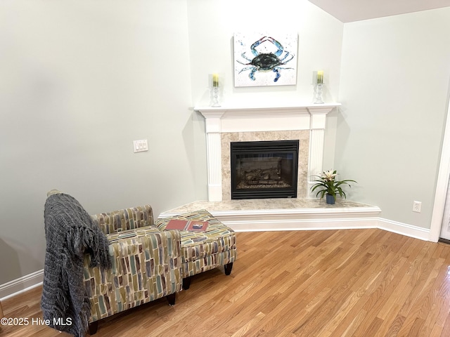 living area with a fireplace, baseboards, and wood finished floors