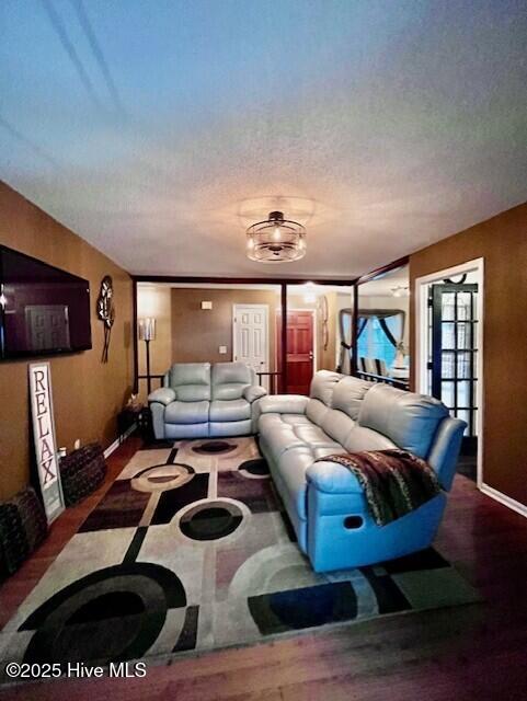 living area featuring a textured ceiling, baseboards, and wood finished floors