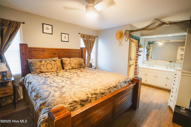 bedroom featuring a sink, a ceiling fan, wood finished floors, and ensuite bathroom