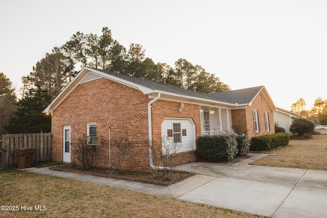 view of property exterior with brick siding, a lawn, and fence