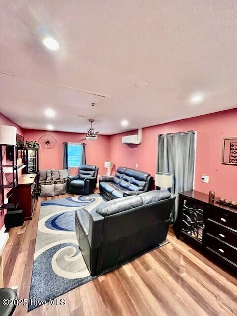 living room with light wood finished floors, a wall mounted AC, and recessed lighting