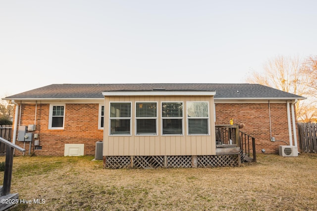 rear view of property featuring brick siding, a lawn, and fence