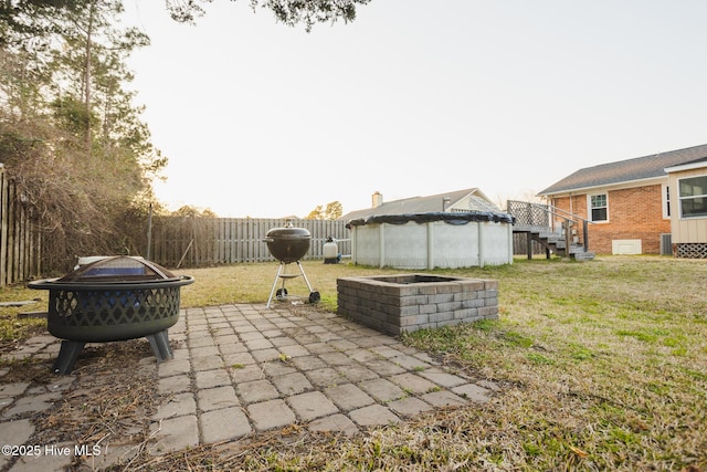 view of yard featuring fence, a fire pit, and a swimming pool