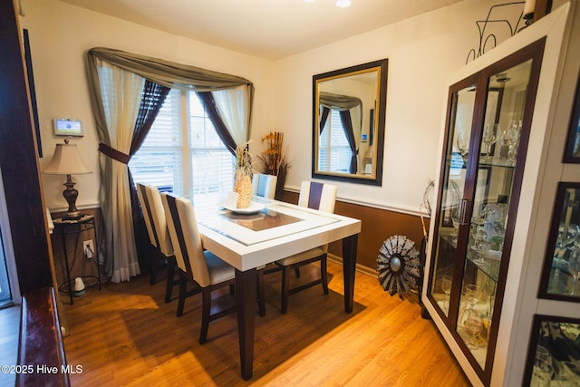 dining space featuring light wood-style floors and a wainscoted wall