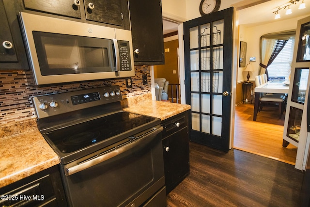 kitchen with dark cabinets, stainless steel appliances, light countertops, decorative backsplash, and dark wood finished floors