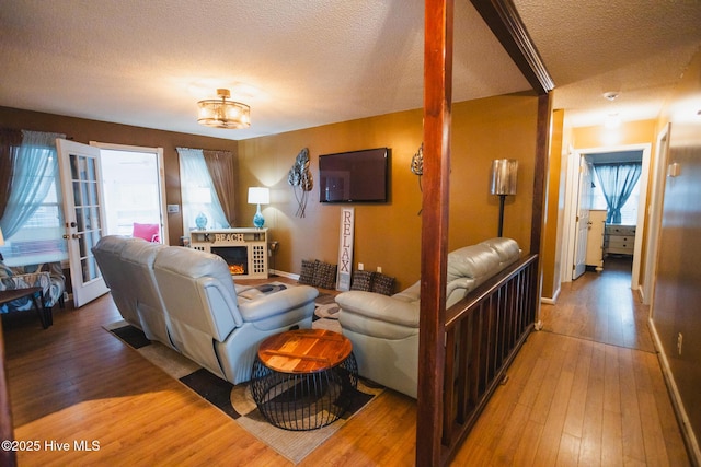 living area with a textured ceiling, baseboards, hardwood / wood-style floors, and french doors