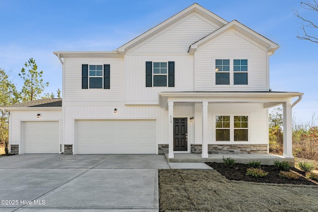 view of front facade with a porch, stone siding, driveway, and a garage