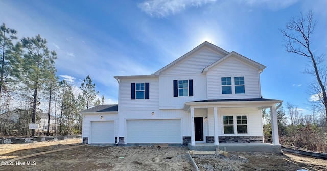 view of front of home featuring dirt driveway, stone siding, a porch, and a garage