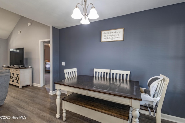 dining area featuring lofted ceiling, baseboards, a chandelier, and wood finished floors