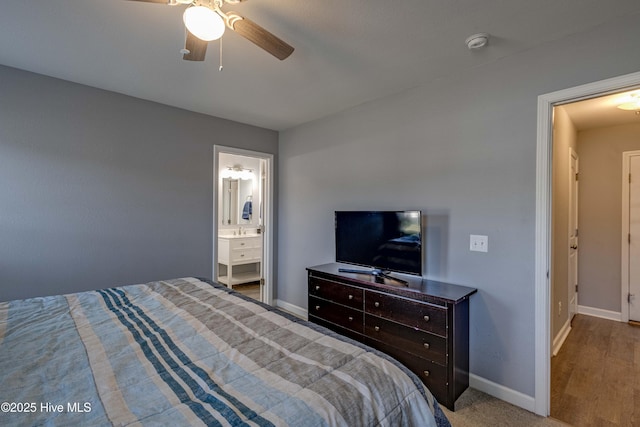 bedroom with ceiling fan, ensuite bath, and baseboards