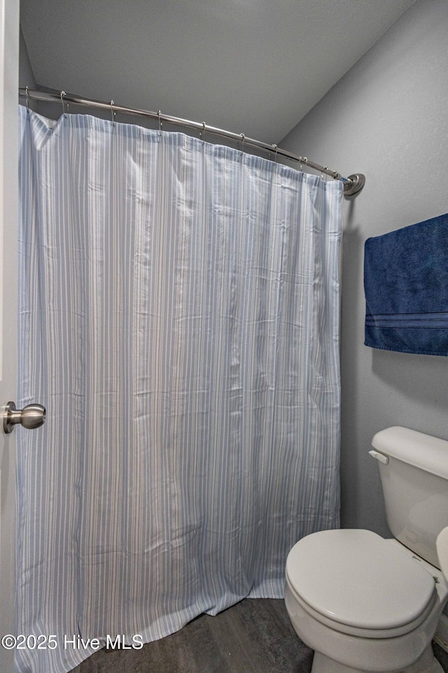 bathroom with curtained shower and toilet