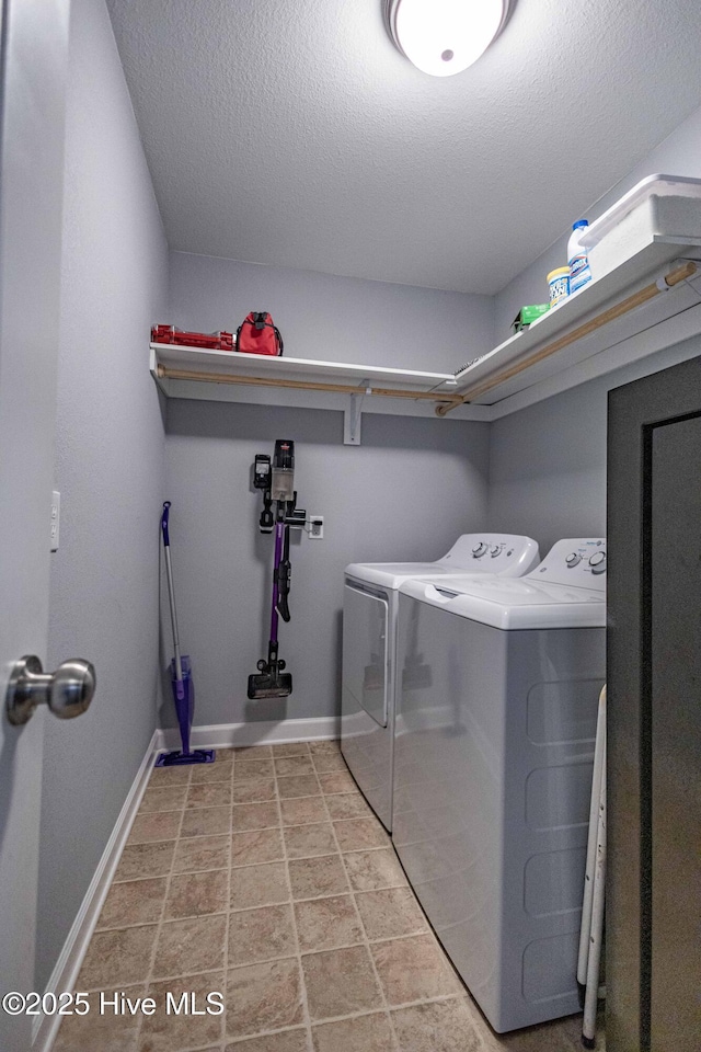 washroom with a textured ceiling, laundry area, washing machine and clothes dryer, and baseboards